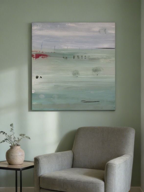 Abstract landscape painting hung above a beige armchair with a small side table and ceramic vase on a green wall
