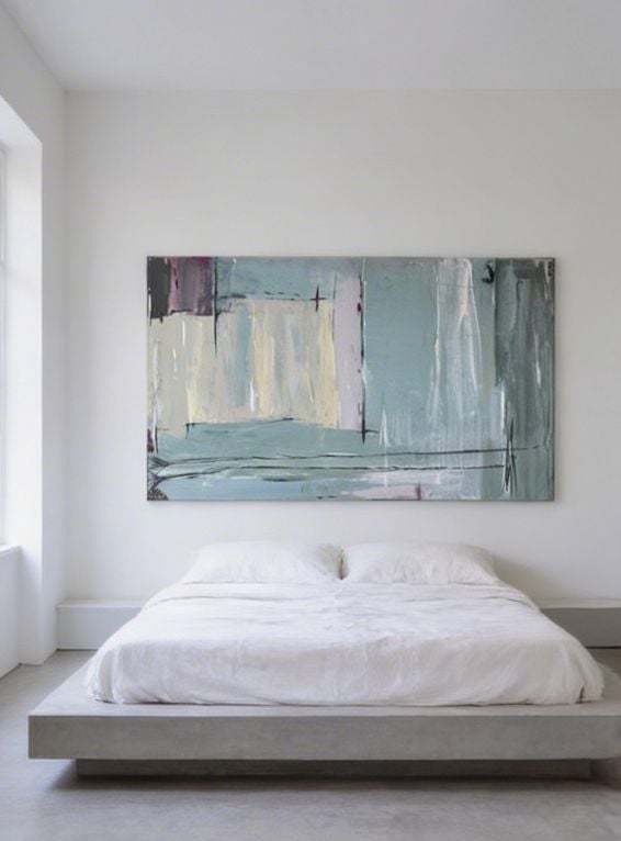 Modern minimalist bedroom with a low-profile platform bed with white bedding beneath an abstract landscape painting in muted tones