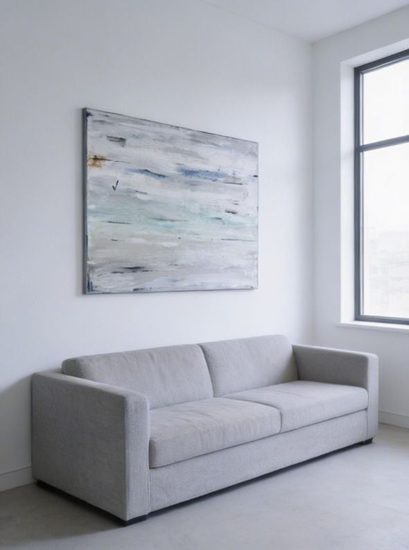 Minimalist living room with gray upholstered sofa, abstract landscape painting on white wall, and large window with dark frame